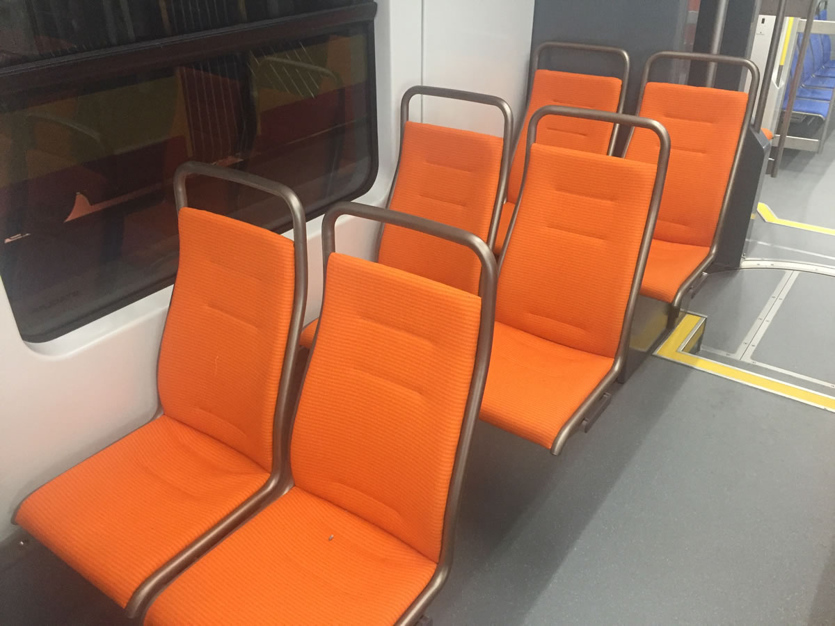 Rows of orange upholstered rail passenger seats