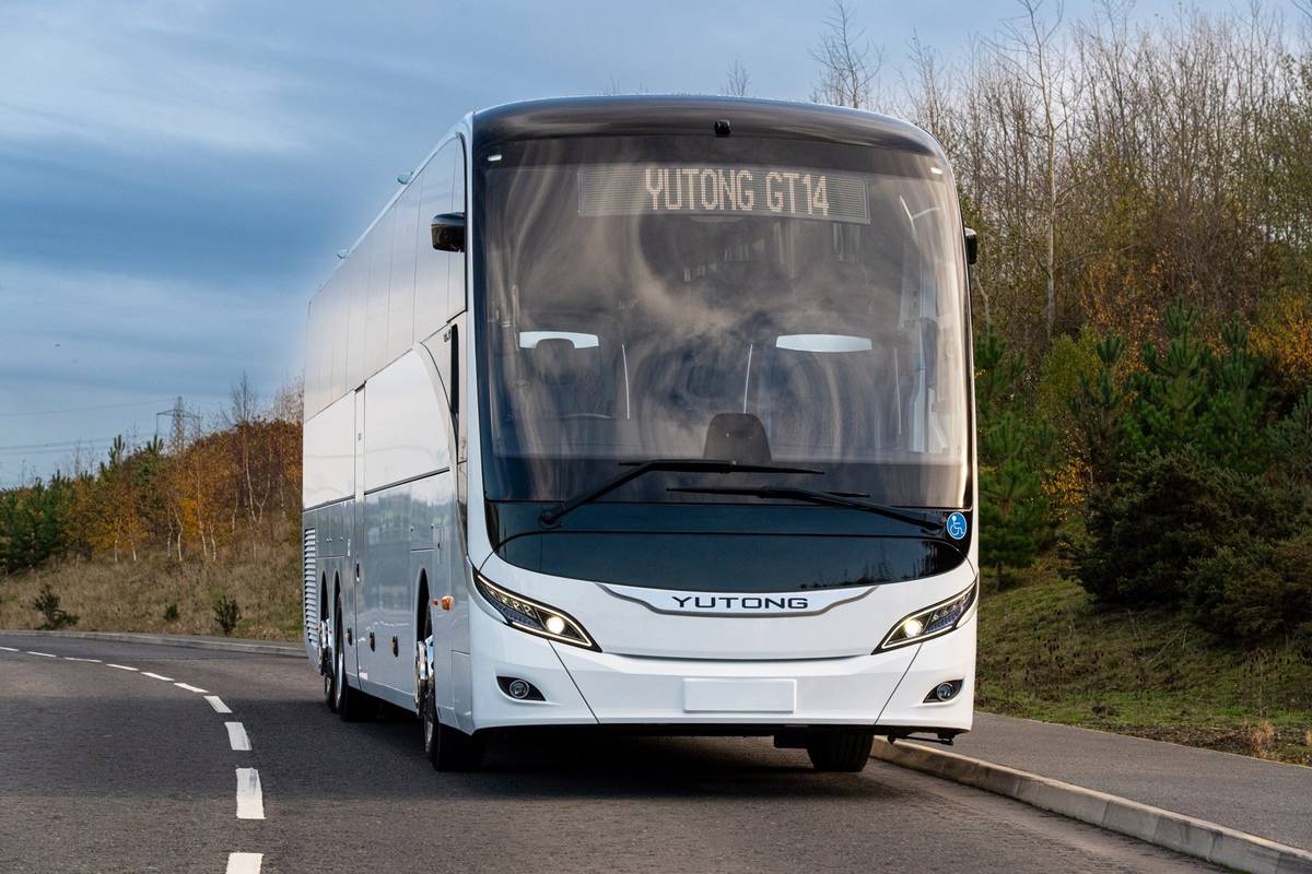 White Yutong GT14 tri-axle coach on a country road