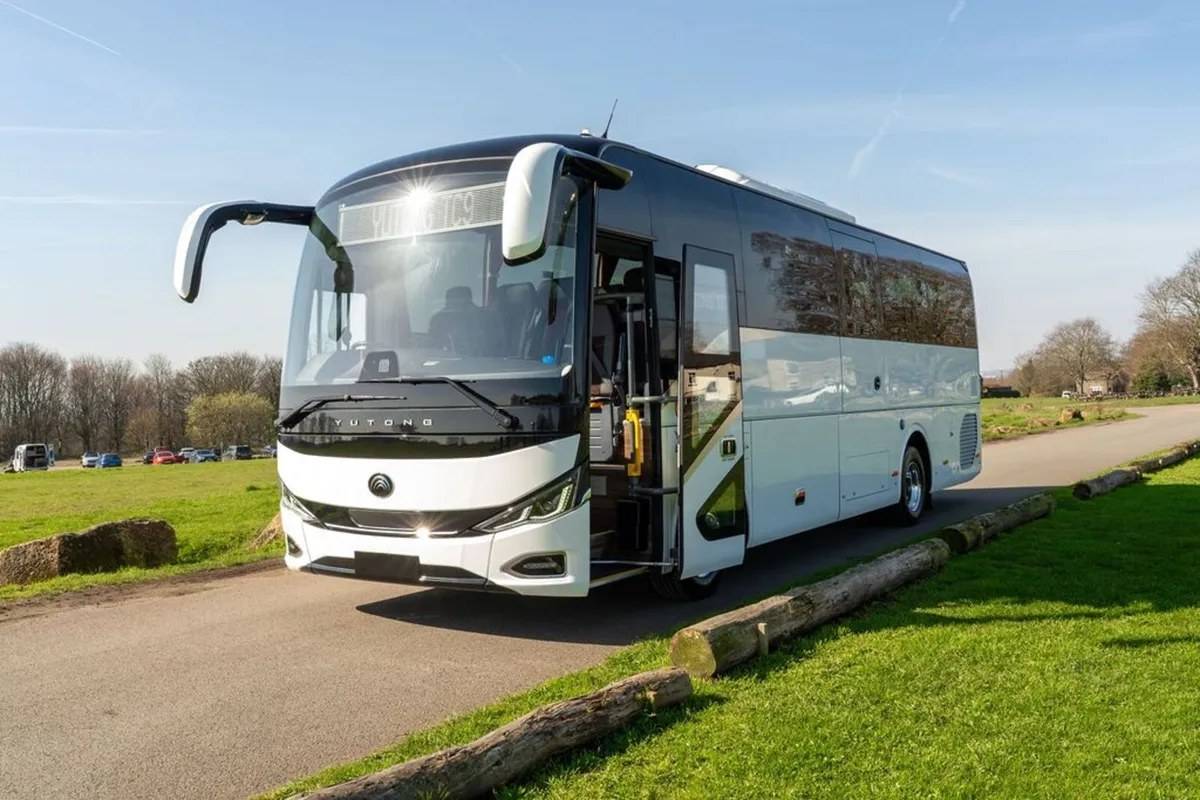 White Yutong TC9 midi coach parked on a road beside grass